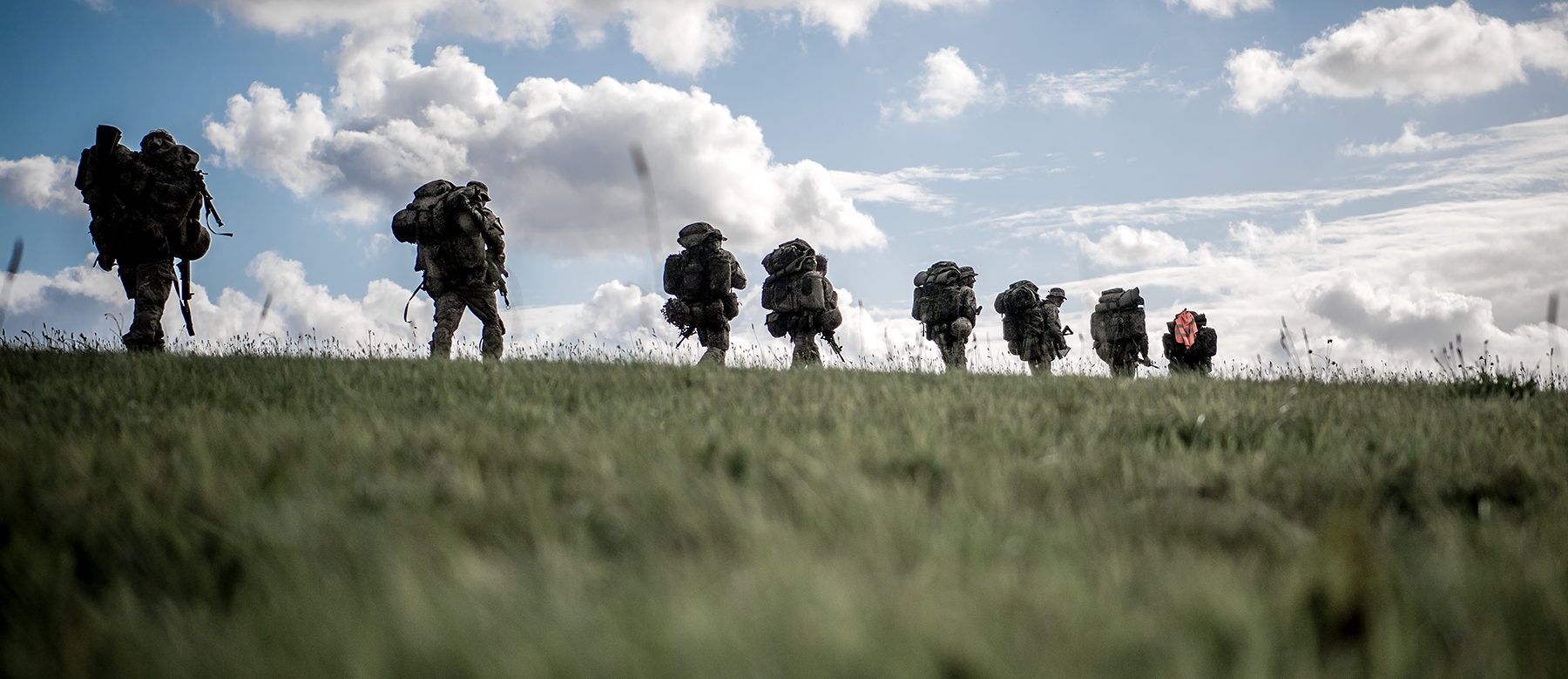 Soldater med oppakning marcherer på en mark
